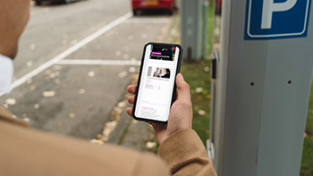 Uomo al telefono cellulare in piedi all'esterno che guarda la lista di controllo per la ricerca di un agente di acquisto