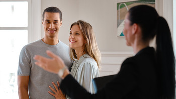 Une courtière présente un appartement à un jeune couple dans le cadre d’une visite