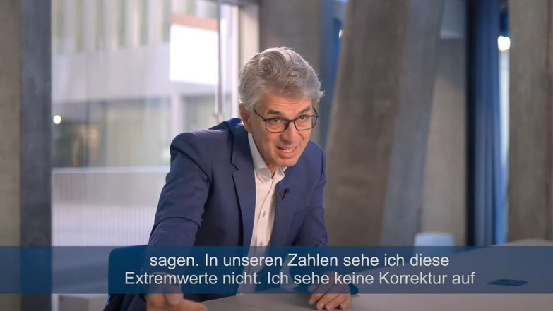 Mann vor der Kamera in einem Büro sitzend
