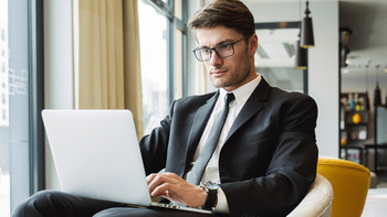 Uomo in abito è seduto in un caffè davanti a un laptop