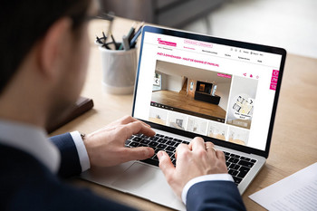 Un homme est assis devant un ordinateur portable et consulte une annonce immobilière