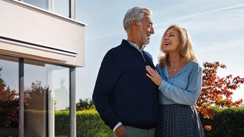 Un couple heureux se tient devant une belle maison et se regarde langoureusement