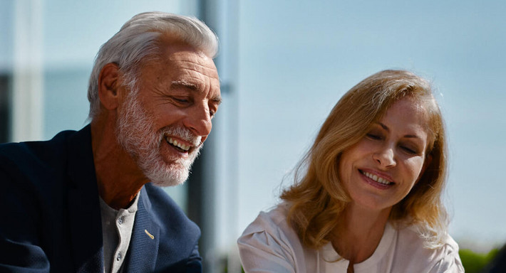 Un couple d’un certain âge signe un formulaire avec le sourire