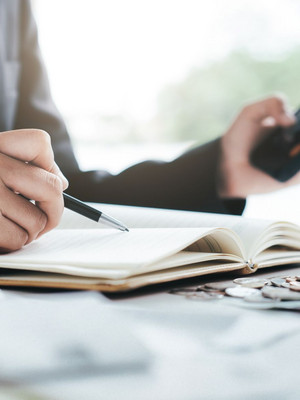 Personne en costume avec une calculatrice tenant un stylo à la main