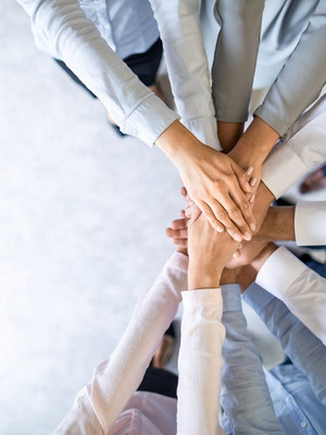 Hände berühren sich in der Mitte und formen einen Kreis, um Teamwork zu symbolisieren