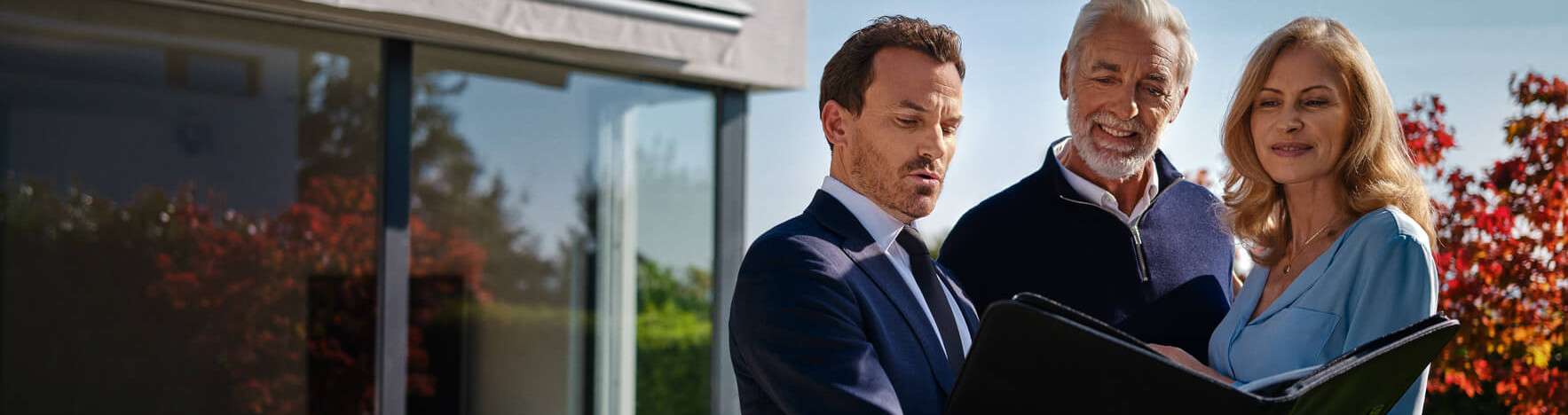 L'agent immobilier se tient dans le jardin avec un couple âgé et discute de la propriété