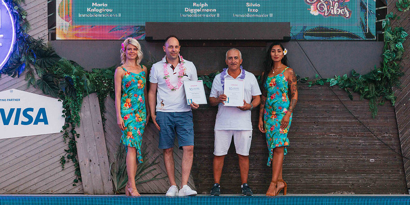 Männer halten Urkunde auf Foto mit Hostessen im Hawaii Kleid
