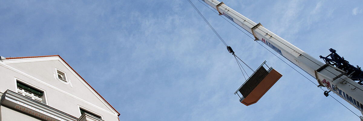 Kran hebt Bauteil auf Gebäude