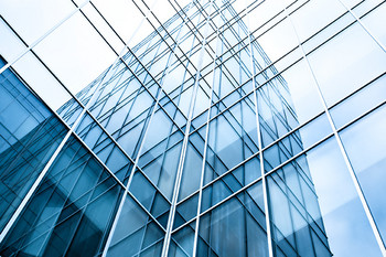 Verglastes Bürogebäude mit Hochhaus im Hintergrund