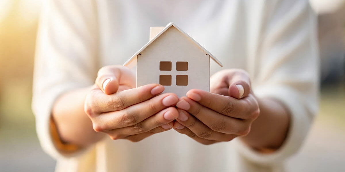 Person hält Modellhaus mit zwei Händen