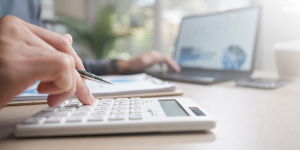 Mann tippt an Tisch auf Taschenrechner 