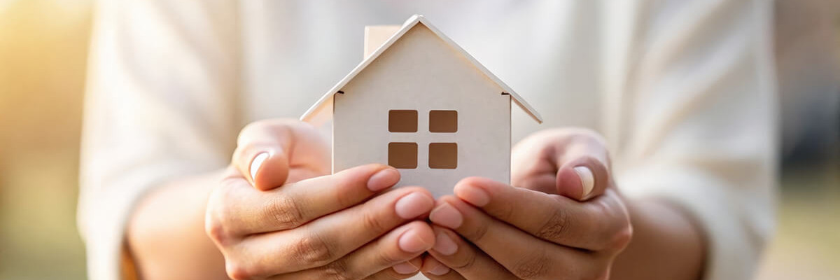 Person hält Modellhaus mit zwei Händen