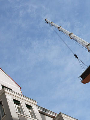 Kran hebt Bauteil auf Gebäude 