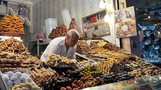 Marktstand mit älterem Herr and der Kasse und vielen verschiedenen Früchten