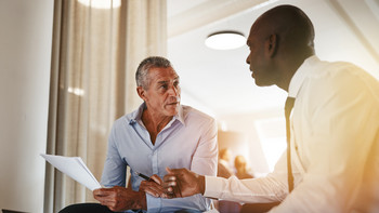 Zwei Männer diskutieren in der Abendsonne im Büro über ein Dokument