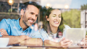 Un jeune couple consulte des offres immobilières sur une tablette