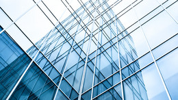 Verglastes Bürogebäude mit Hochhaus im Hintergrund