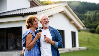 Un couple âgé se tient dans les bras l'un de l'autre et sourit au loin.