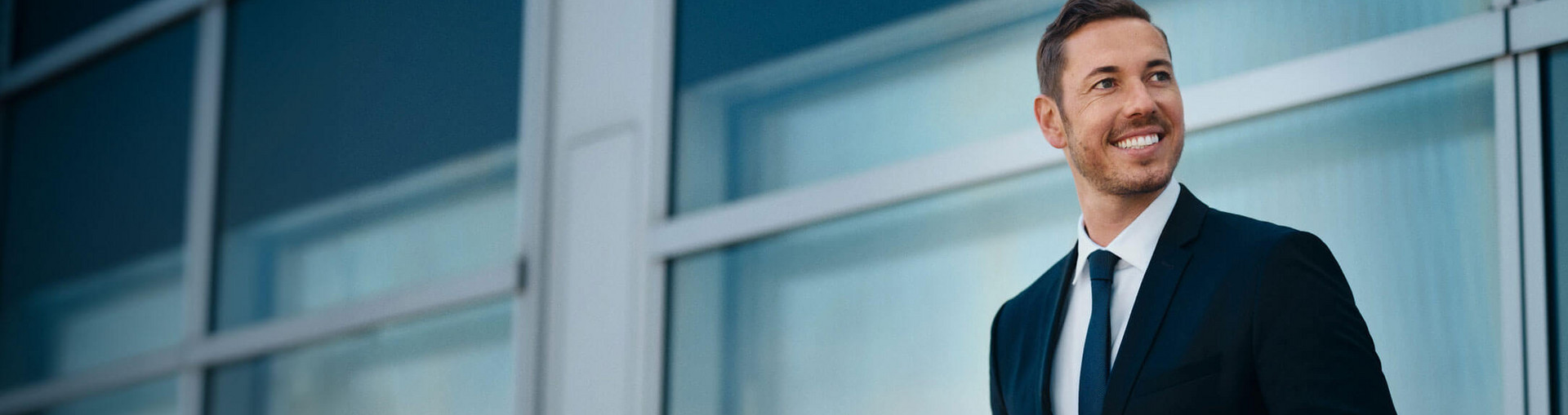 Il broker si trova davanti a un vetro e guarda in lontananza.