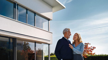 Un couple heureux se tient devant une belle maison et se regarde avec amour