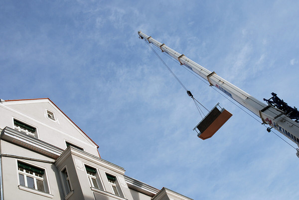 Kran hebt Bauteil auf Gebäude 