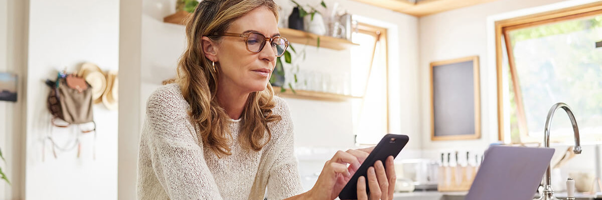 Frau an Handy mit Laptop und Dokumenten