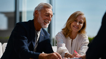 Älteres Ehepaar unterschreibt lächelnd ein Formular