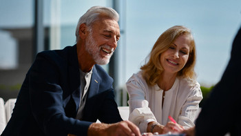 Un couple d’un certain âge signe un formulaire avec le sourire