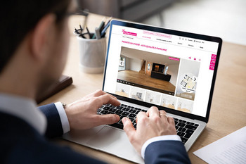 Un uomo è seduto davanti a un laptop e guarda un annuncio immobiliare