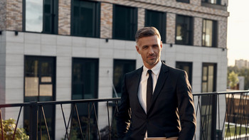 Uomo in giacca e cravatta davanti a un edificio moderno