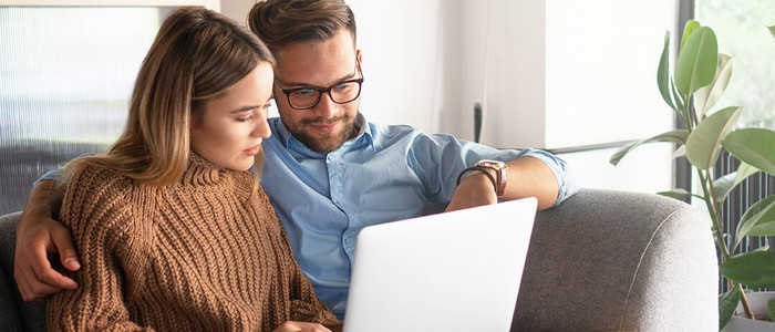 Paar auf Sofa schaut auf Laptop
