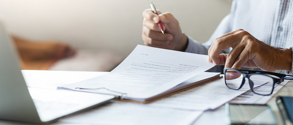 Person unterschriebt Dokumente auf Tisch