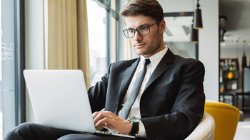 Uomo in abito è seduto in un caffè davanti a un laptop