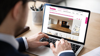 Mann sitzt vor einem Laptop und sieht sich ein Immobilieninserat an