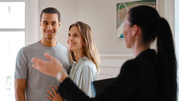 Une courtière présente un appartement à un jeune couple dans le cadre d’une visite