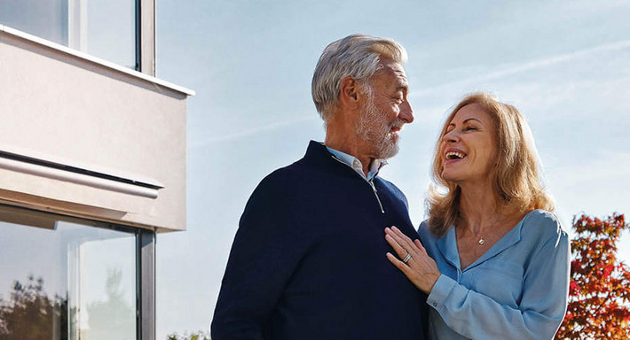 Un couple heureux se tient devant une belle maison et se regarde langoureusement