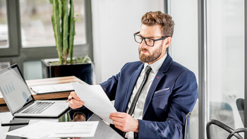 Un jeune homme en complet examine des documents sur un bureau