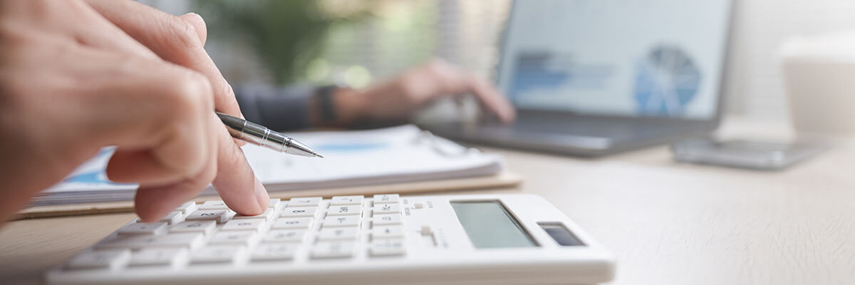 Mann tippt an Tisch auf Taschenrechner 